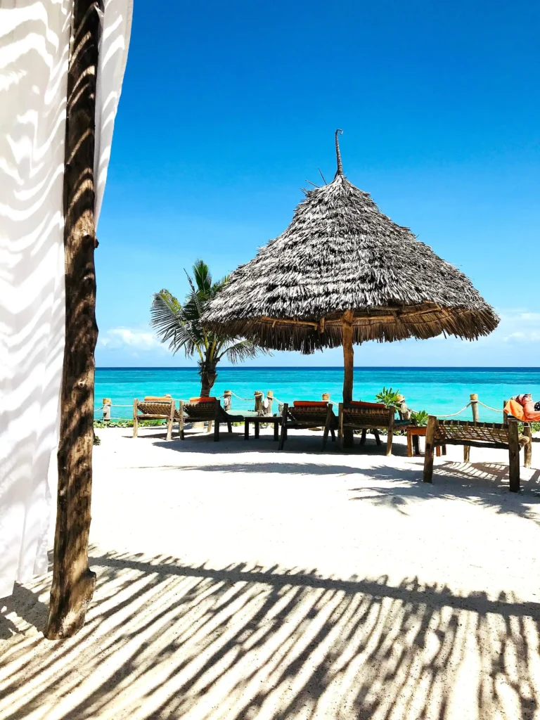 An image of thatched resting area and beach beds on a beach in Zanzibar